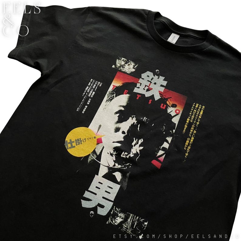 Puede incluir: Camiseta negra con un dise&ntilde;o gr&aacute;fico que presenta texto japon&eacute;s y un retrato. El dise&ntilde;o incluye acentos rojos, blancos y amarillos. La palabra "Tetsuo" es visible.