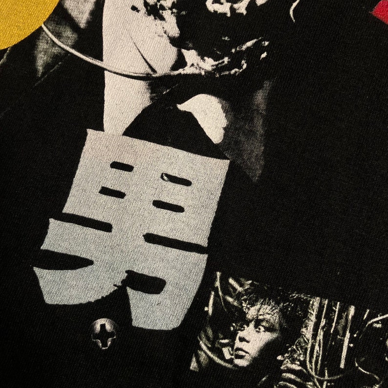 Puede incluir: Camiseta negra con un dise&ntilde;o gr&aacute;fico que presenta un car&aacute;cter japon&eacute;s estilizado y un collage de im&aacute;genes en blanco y negro. El dise&ntilde;o incluye un elemento en forma de cruz y un retrato.