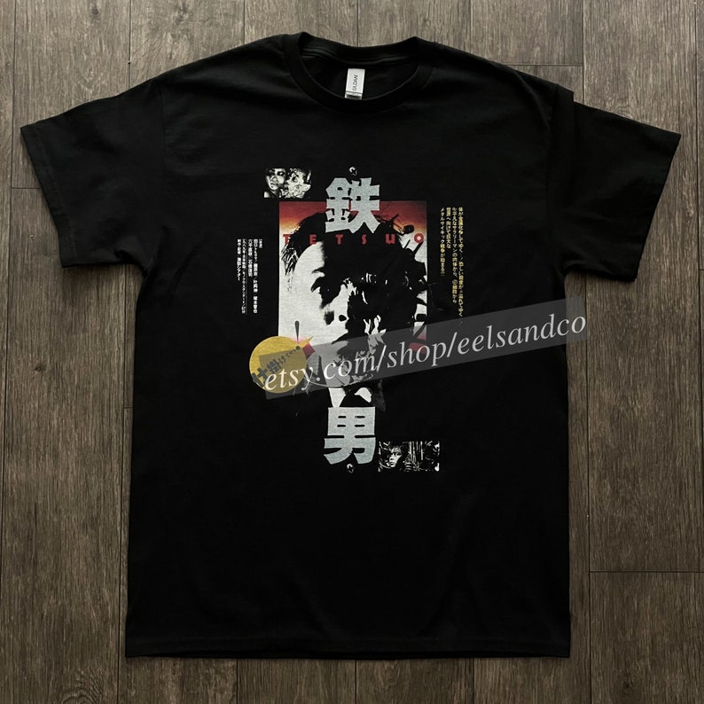 Puede incluir: Camiseta negra con un dise&ntilde;o gr&aacute;fico que incorpora texto japon&eacute;s y un rostro estilizado. El dise&ntilde;o utiliza elementos rojos, blancos y negros. La palabra "TETSUO" es visible.