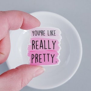 May include: A pink and white sticker with the text "You're like really pretty." The sticker has a watercolor-like design.