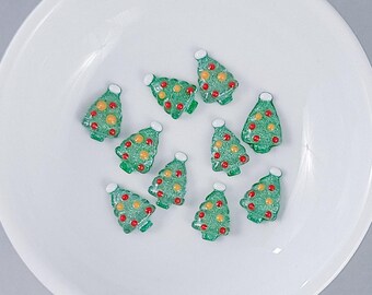 Può includere: Un piatto bianco con dieci ornamenti per albero di Natale verdi. Gli ornamenti sono decorati con glitter rosso e giallo.