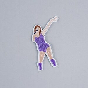 May include: Purple embroidered iron-on patch of a person singing into a microphone.