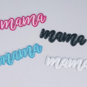 May include: Four glittery "mama" word cutouts in pink, black, blue, and white. The cursive text is outlined with glitter, creating a sparkling effect. These decorative cutouts are ideal for crafting projects.