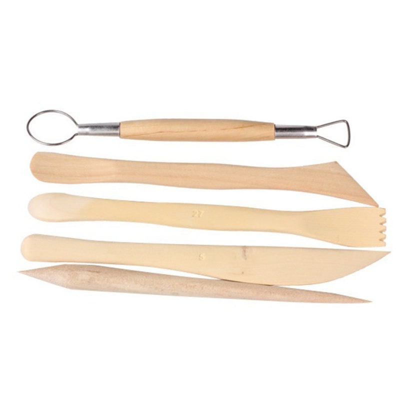 May include: A set of five light-colored wooden pottery tools. The tools include a loop tool, a flat tool, a serrated tool, a knife-shaped tool, and a pointed tool. The tools are designed for sculpting and shaping clay.