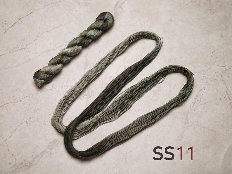 Op de afbeelding: Twee klossen groene ombre borduurgaren, &eacute;&eacute;n klos is gedraaid en de andere ligt in een lus. Het garen is ge&euml;tiketteerd met "SS11".