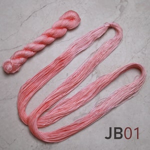 Op de afbeelding: Een bolletje lichtroze borduurgaren, met een lange streng van hetzelfde garen ernaast gelegd. De tekst "JB01" is gedrukt op een witte achtergrond onder het garen.