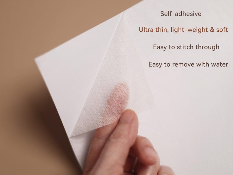 May include: A close-up of a white, self-adhesive material being peeled back, revealing a fingertip. Text on the image reads: Self-adhesive, Ultra thin, light-weight & soft, Easy to stitch through, Easy to remove with water.