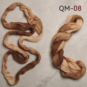 Peut inclure: Deux &eacute;cheveaux de fil aux tons bruns et beiges. L'un est enroul&eacute; en spirale, l'autre est torsad&eacute;. Le texte "QM-08" est imprim&eacute; en haut &agrave; droite.