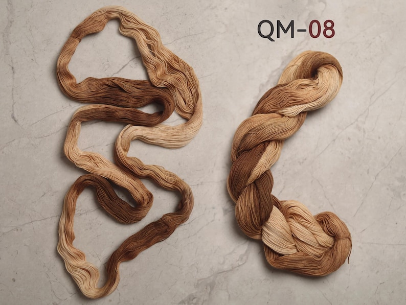 Peut inclure: Deux &eacute;cheveaux de fil aux tons bruns et beiges. L'un est enroul&eacute; en spirale, l'autre est torsad&eacute;. Le texte "QM-08" est imprim&eacute; en haut &agrave; droite.