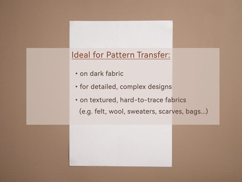 May include: A white rectangular paper with the text "Ideal for Pattern Transfer:" and bullet points listing uses for dark fabric, detailed designs, and textured fabrics like felt, wool, and scarves. The background is a light brown color.