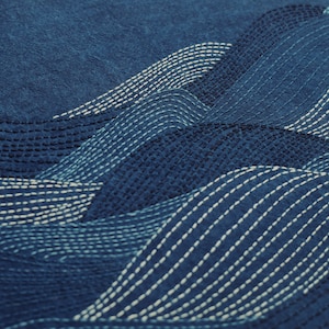 May include: A close-up of a blue fabric with white stitching in a wave pattern.