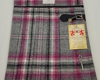 May include: A pink, gray, and white plaid crossbody bag with a black zipper and a leather strap. The bag has a small tag attached to it that reads "Authentic Scottish Product by Calzeat of Scotland".