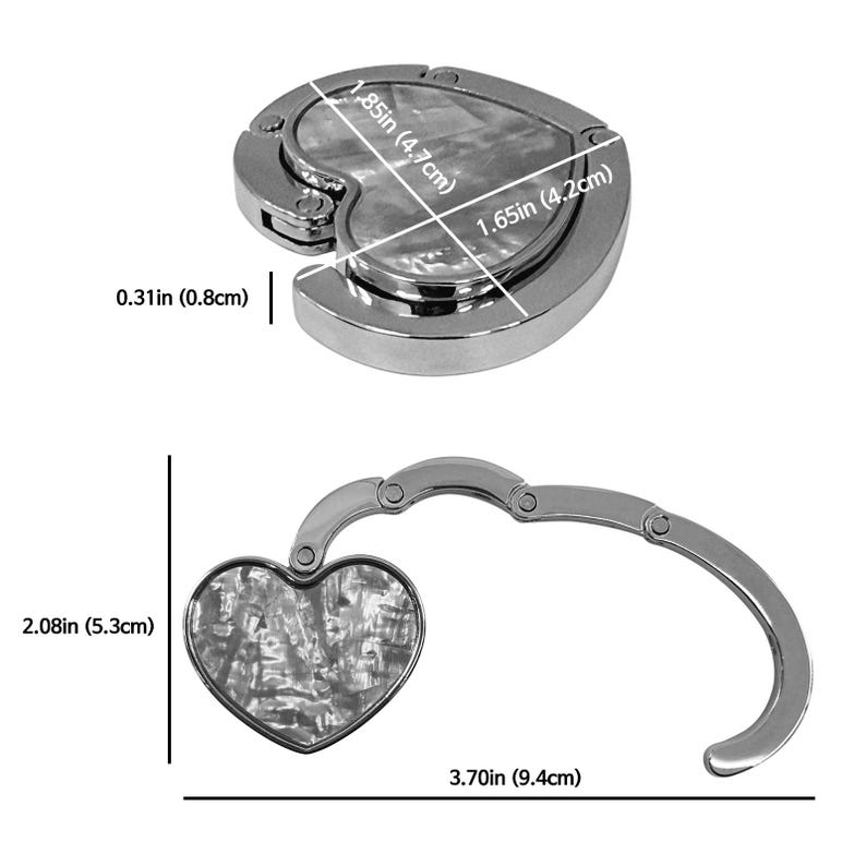 K&ouml;nnte beinhalten: Ein silberfarbener herzf&ouml;rmiger Handtaschenhaken mit Perlmutt-Inlay. Der Haken ist 9,4 cm lang, wenn er ausgeklappt ist, und 5,3 cm hoch. Das Herz ist 4,7 cm x 4,2 cm gro&szlig;.