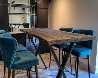 Op de afbeelding: Een donkerhouten eettafel met een zwart metalen frame en vier tealblauwe stoelen. De tafel heeft een live edge-design en staat in een moderne eetkamer.