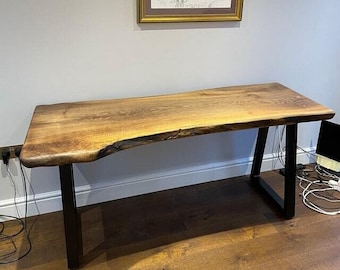 Op de afbeelding: Een rustiek houten bureau met een live edge-blad en zwarte metalen A-vormige poten. Het bureau is gemaakt van natuurlijk hout met een warme bruine kleur en een uniek houtnerfpatroon.