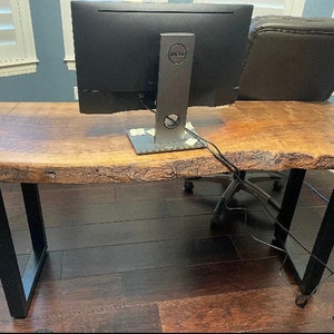 May include: A wooden desk with a live edge top and black metal legs. A Dell computer monitor is on the desk.