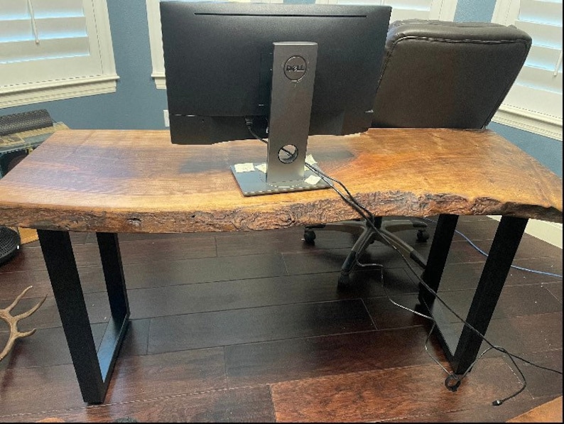 May include: A wooden desk with a live edge top and black metal legs. A Dell computer monitor is on the desk.