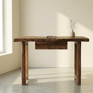 May include: A solid wood desk with a natural finish. The desk has a single drawer and four sturdy legs. A small notebook and a vase with branches are on the desk. The desk is approximately 152 cm long.