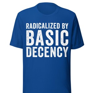 Può includere: T-shirt blu reale con la scritta bianca "RADICALIZED BY BASIC DECENCY" in un carattere audace e invecchiato. La maglietta ha un girocollo e maniche corte. Il testo è centrato sul davanti.