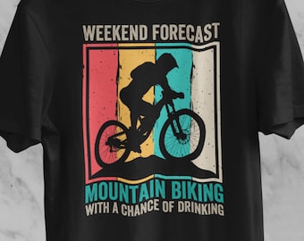 May include: Black t-shirt with a vintage-style graphic of a person mountain biking. The graphic has a red, orange, yellow, blue, and green color scheme. The text reads "Weekend Forecast Mountain Biking With A Chance Of Drinking".