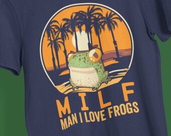 May include: A navy blue t-shirt with a cartoon frog in a sunset scene with palm trees. The text "MILF MAN I LOVE FROGS" is printed below the image.