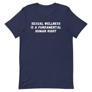 Puede incluir: Una camiseta azul marino con el texto "SEXUAL WELLNESS IS A FUNDAMENTAL HUMAN RIGHT" impreso en blanco.