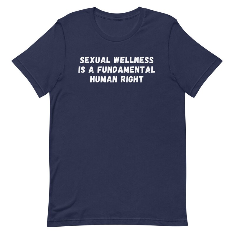 Puede incluir: Una camiseta azul marino con el texto "SEXUAL WELLNESS IS A FUNDAMENTAL HUMAN RIGHT" impreso en blanco.