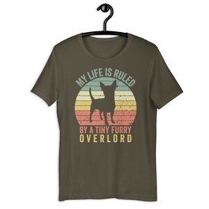 Op de afbeelding: Een bruin T-shirt met een vintage-stijl afbeelding van een chihuahua voor een zonsondergang. De tekst luidt "Mijn leven wordt geregeerd door een kleine harige overlord."
