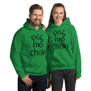 Puede incluir: Dos personas con sudaderas con capucha verdes a juego. Cada sudadera tiene el texto "G&oacute;s mo ch&oacute;in" en negro. Las sudaderas tienen un bolsillo delantero y una capucha. Las personas est&aacute;n sonriendo.