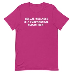 Puede incluir: Una camiseta rosa con el texto "SEXUAL WELLNESS IS A FUNDAMENTAL HUMAN RIGHT" impreso en blanco.