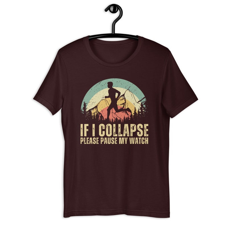 May include: A maroon t-shirt with a vintage-style graphic of a runner in front of mountains. The text "IF I COLLAPSE PLEASE PAUSE MY WATCH" is printed below the graphic.