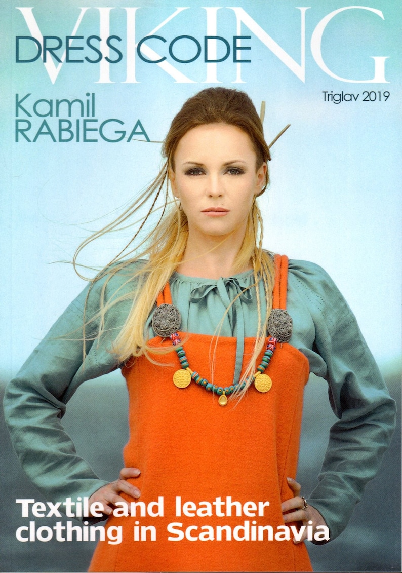 Op de afbeelding: Een vrouw draagt een turquoise shirt en een oranje jurk met een gouden en groene kralenketting. De tekst "Dress Code" staat bovenaan de afbeelding. De tekst "Viking" is gedeeltelijk zichtbaar bovenaan de afbeelding. De tekst "Kamil Rabiega" staat linksboven in de afbeelding. De tekst "Triglav 2019" staat rechtsboven in de afbeelding. De tekst "Textile and leather clothing in Scandinavia" staat onderaan de afbeelding.