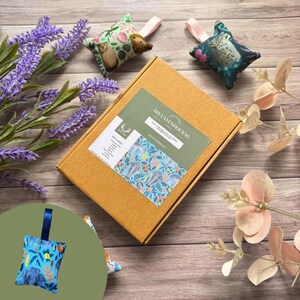 May include: A DIY lavender bag kit featuring a cardboard box, three decorative sachets, and lavender sprigs. The box has a green label with the text "DIY Lavender Bag" and a blue floral pattern. The sachets have animal and floral patterns.
