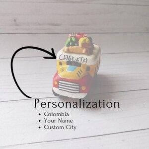 May include: A yellow and red toy bus with the word "Chiquita" on the side. The bus is decorated with green and yellow fruit and vegetables. The bus is a personalized gift with the option to add a name and city.