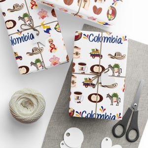 May include: White wrapping paper with a repeating pattern of Colombian cultural icons, including coffee cups, hats, and donkeys carrying goods. The word "Colombia" is written in blue. Tied with twine.