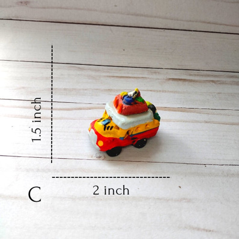 May include: A small, colorful, hand-painted ceramic bus figurine with luggage on the roof. The bus is approximately 2 inches long and 1.5 inches tall.