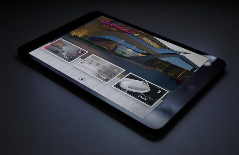 Op de afbeelding: Een zwarte tablet met een website met het logo "VARMORA" en afbeeldingen van tegels en sanitair. De tablet ligt op een donkere ondergrond, met een lichte reflectie.