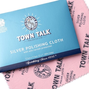May include: A blue and white box with the text "Town Talk Polish Co Ltd" and "Silver Polishing Cloth with anti-tarnish protection". The box is sitting on top of a pink polishing cloth with the same logo.