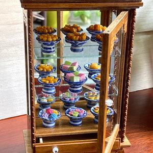 Models of miniature Thai desserts in beautiful colors in a beautifully carved wood cabinet.