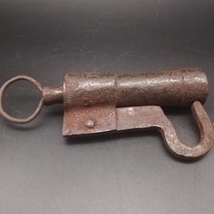 May include: A rusty metal padlock with a hook and a keyhole. The padlock has a key attached to it.