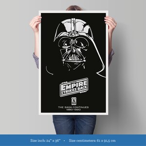 K&ouml;nnte beinhalten: Ein Schwarzwei&szlig;-Poster mit Darth Vader aus dem Film Star Wars: Das Imperium schl&auml;gt zur&uuml;ck. Das Poster enth&auml;lt den Filmtitel und den Text "Die Saga geht weiter 1980-1990". Das Poster misst 61 Zentimeter mal 91,5 Zentimeter.