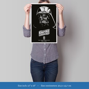 K&ouml;nnte beinhalten: Ein Schwarzwei&szlig;-Poster mit Darth Vader aus dem Film Star Wars: Das Imperium schl&auml;gt zur&uuml;ck. Der Text auf dem Poster lautet "Star Wars: Das Imperium schl&auml;gt zur&uuml;ck" und "Die Saga geht weiter 1980-1990". Das Poster ist 30,5 Zentimeter mal 45,7 Zentimeter gro&szlig;.