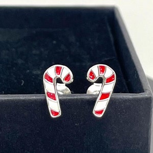 May include: A pair of silver candy cane earrings with red and white enamel. The earrings are in a black box.