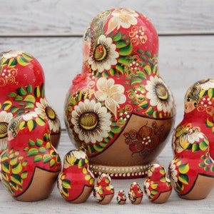 May include: A set of traditional Russian nesting dolls, or Matryoshka dolls, in various sizes. The dolls are painted red with floral and gold accents. The largest doll is approximately 7 inches tall.
