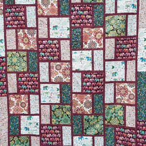 Peut inclure: Une courtepointe patchwork avec un fond bordeaux et diverses cases color&eacute;es repr&eacute;sentant des motifs floraux et d'&eacute;l&eacute;phants.