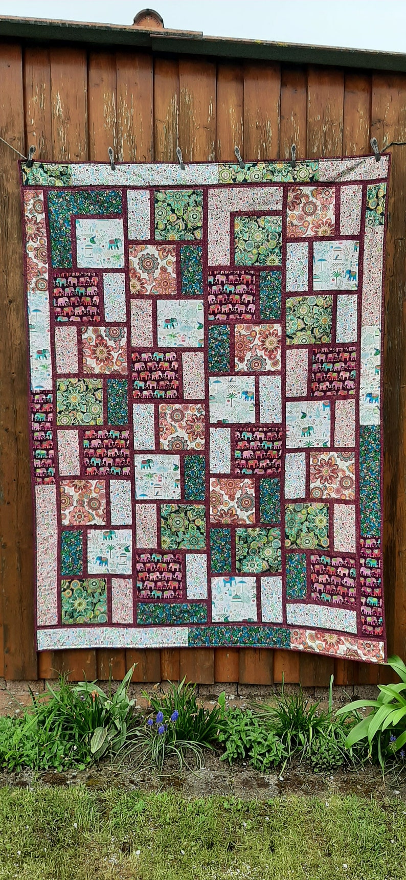 Peut inclure: Une courtepointe patchwork avec un motif g&eacute;om&eacute;trique pr&eacute;sentant diff&eacute;rentes nuances de vert, de rouge et de blanc. La courtepointe est compos&eacute;e de carr&eacute;s et de rectangles avec diff&eacute;rents motifs, notamment des &eacute;l&eacute;phants, des fleurs et des motifs paisley.