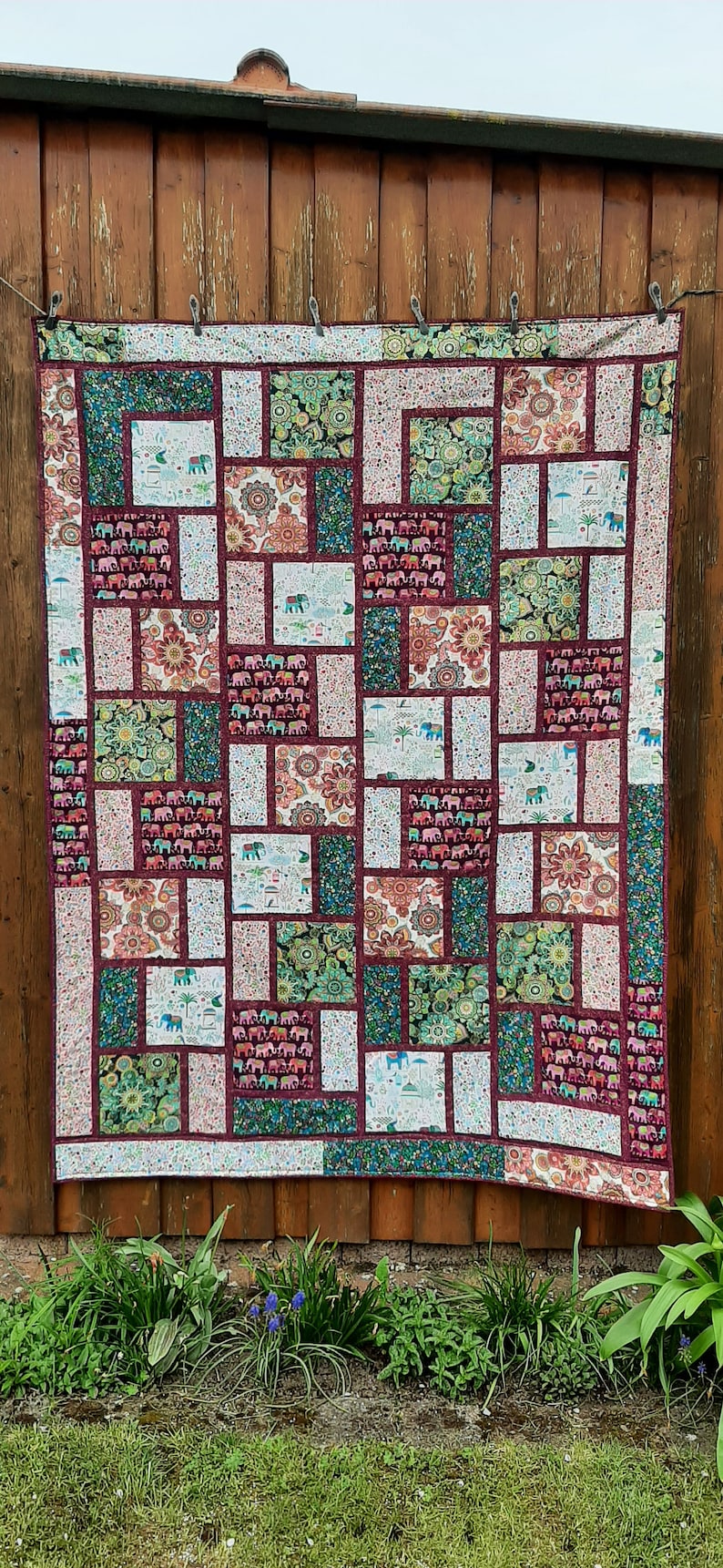 Peut inclure: Une courtepointe color&eacute;e avec un motif de patchwork repr&eacute;sentant des &eacute;l&eacute;phants, des fleurs et des motifs g&eacute;om&eacute;triques. La courtepointe est faite de diff&eacute;rents tissus dans des tons de vert, rouge, blanc et bleu.