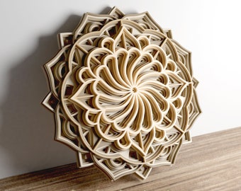 Könnte beinhalten: Ein mehrschichtiges Holzmandala mit einem komplizierten Design, das ein wirbelndes Muster in der Mitte zeigt. Das Mandala besteht aus mehreren Holzschichten, die einen 3D-Effekt erzeugen. Das Mandala ist ein beliebtes Dekorationselement für Häuser und Büros.