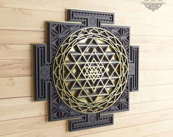 May include: A black and gold geometric design with intricate details. The design is a Sri Yantra, a sacred symbol in Hinduism. The design is on a wooden background.