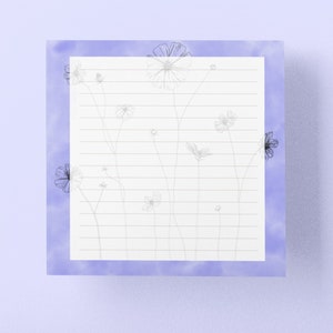 May include: A white lined notepad with a light blue watercolor border and a black and white floral design.